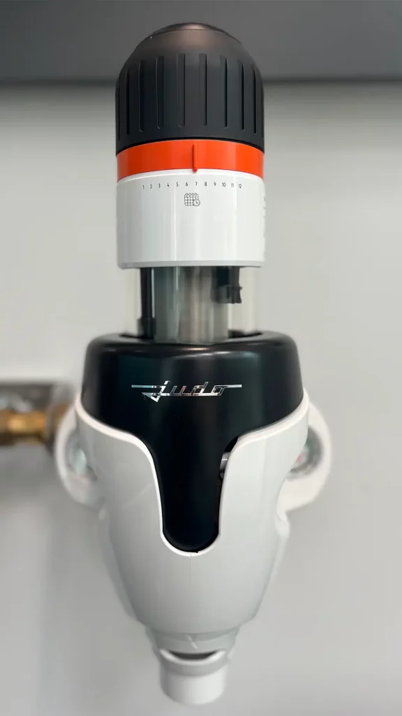 Nahaufnahme eines installierten Wasserfiltersystems mit Einstellring und transparenter Filterkammer.