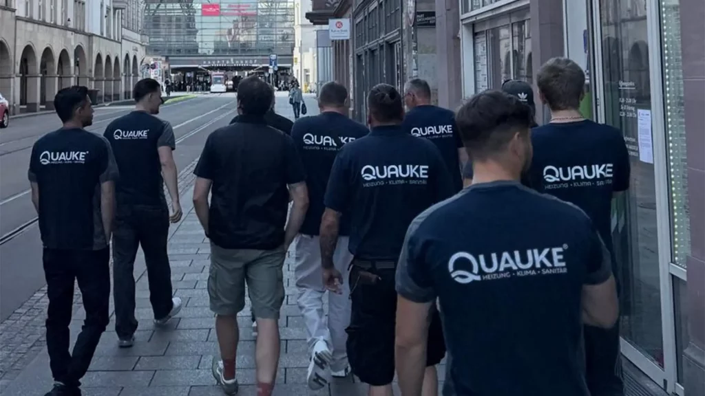 Mitarbeitende der Quauke GmbH gehen gemeinsam in Unternehmenskleidung durch die Innenstadt auf dem Weg zum Viega Seminarcenter.