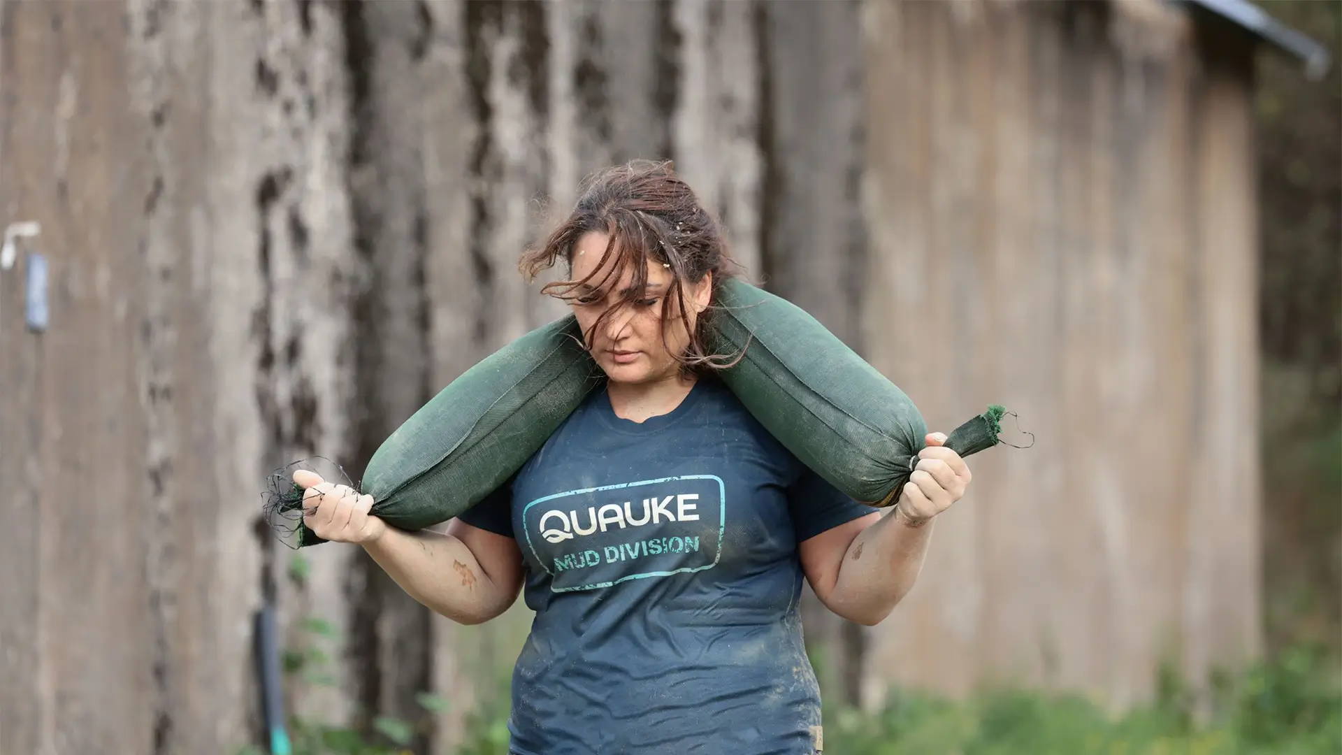 Teilnehmerin des Quauke-Teams bewältigt mit einem Sandsack ein Hindernis beim Mud Masters.